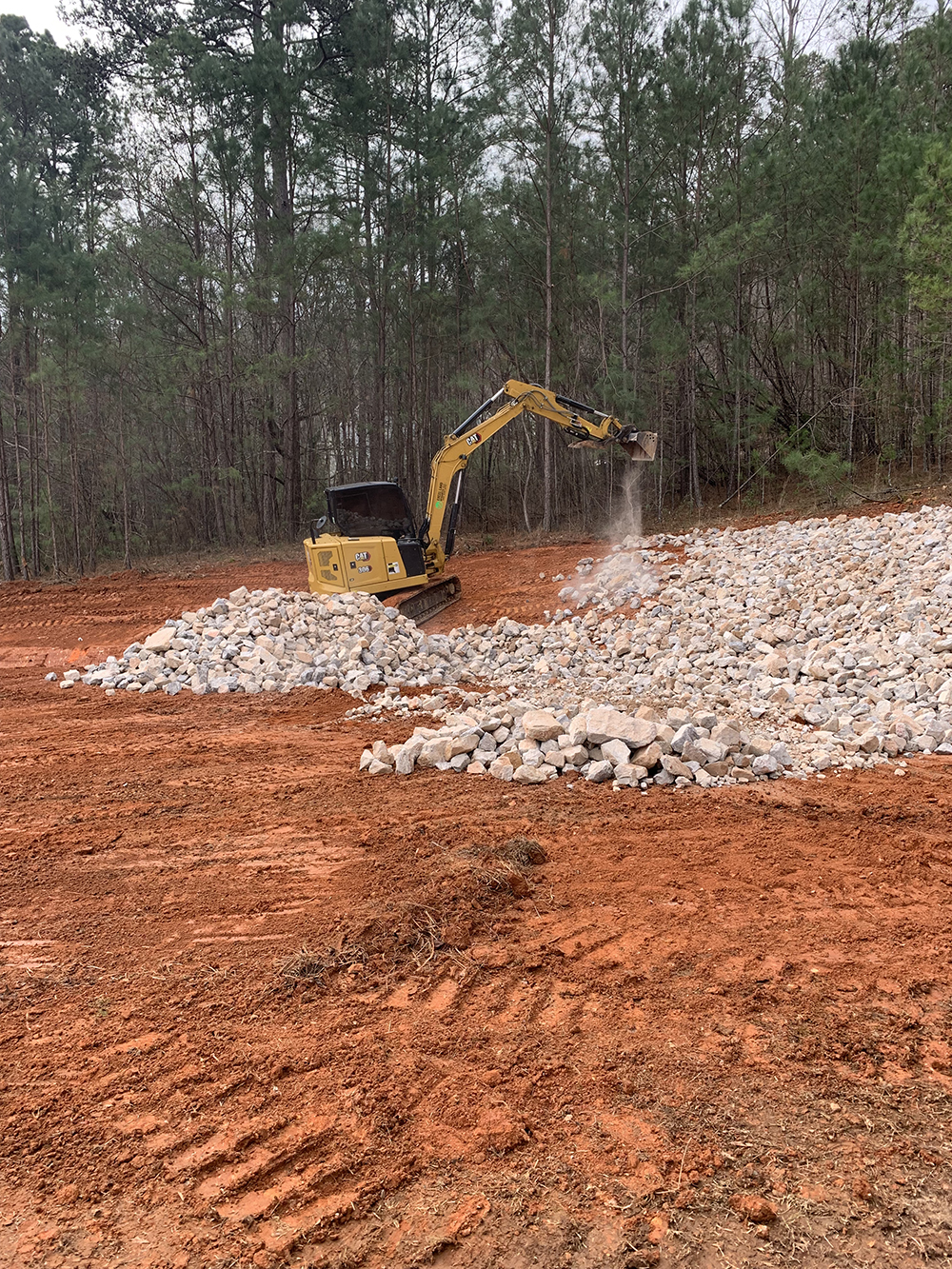 excavator clearing land with rocks